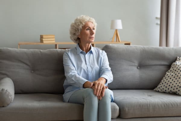 senior woman sitting on a sofa, hands crossed and thoughtful attitude